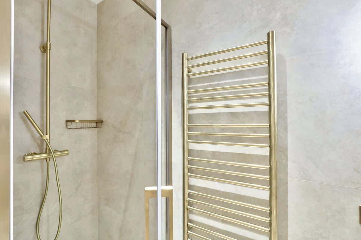 Un baño con ducha, toallero y mampara de vidrio.