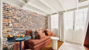 Un salon chaleureux avec un mur en briques, un canapé, une petite table ronde et une fenêtre avec des rideaux.