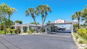 A hotel with a covered entrance, palm trees, and a clear blue sky. - Cozy 2 Queen Bed Studio in Sunny Fort Myers Beach (Fort Myers Beach)