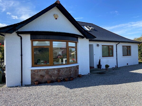 A house with a stone foundation, a pitched roof, and a gravel driveway. - 26 Green Drive (Inverness)