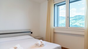Een hotelkamer met een bed, een raam met gordijnen en uitzicht op een landschap.