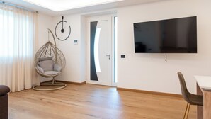 Een moderne woonkamer met een hangstoel, een flatscreen televisie en een houten vloer.
