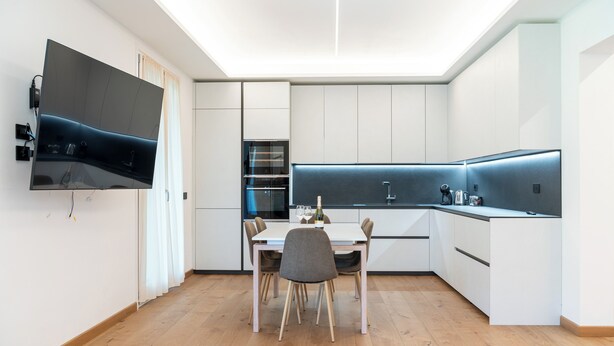 Een moderne keuken met een eethoek, ingebouwde apparatuur en een flatscreen televisie.
