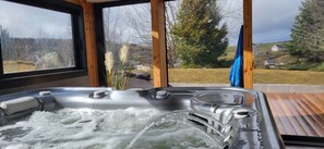 A hot tub with a view of a rural landscape through large windows. - Relaxation between lakes and mountains JoAli 4 * Gîte (SAULZET-LE FROID)