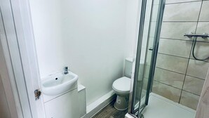 Ein kleines Badezimmer mit Waschbecken, Toilette und Duschkabine aus Glas.