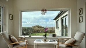 A room with a large window, two chairs, a small table, and a dreamcatcher. - Cottage 498 - Cleggan - sleeps 9 guests  in 4 bedrooms (Cleggan)