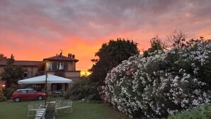 A house with a patio, a car, and a garden with flowering plants. - Room 'Stanza 1' with Mountain View, Wi-Fi and Air Conditioning (Casano)