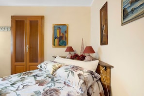 Une chambre à coucher avec un lit, une armoire en bois et deux tableaux accrochés au mur.