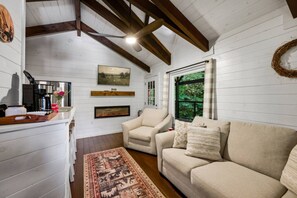 A cozy living room with a fireplace, a sofa, a chair, and a coffee table. - 5BDR Modern Farm Compound: Pool, Hot Tubs, Trails (Sevierville)