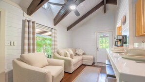 Una habitación acogedora con sofá, sillón, zona de cocina y vistas por la ventana.