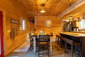 A wooden interior with a dining table, chairs, a kitchen area, and a clock on the wall. - 5BDR Modern Farm Compound: Pool, Hot Tubs, Trails (Sevierville)