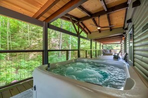 A hot tub in a covered outdoor area with a view of a forest. - 5BDR Modern Farm Compound: Pool, Hot Tubs, Trails (Sevierville)