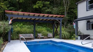 Una piscina con cubierta de madera y sillones de descanso.