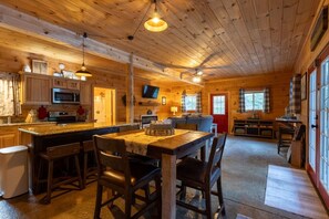 A wooden cabin interior with a kitchen, dining area, and living space. - 5BDR Modern Farm Compound: Pool, Hot Tubs, Trails (Sevierville)