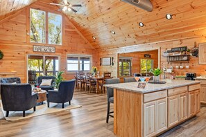 Une cabane spacieuse comprenant un coin repas, une cuisine et une pancarte accueillant les visiteurs.