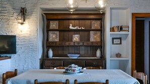 A dining area with a table set for four, a decorative wall with shelves, and a television mounted on the wall. - Villa La Colombaia on Elba Island (Campo nell'Elba)
