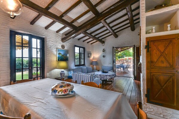 Un coin repas rustique avec une table dressée pour deux personnes, un canapé et une porte en bois.