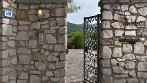 A stone wall with a metal gate, a house number sign, and a potted plant. - Villa La Colombaia on Elba Island (Campo nell'Elba)