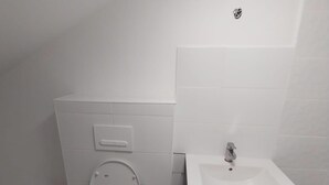 A bathroom with a toilet, a sink, and a cabinet.