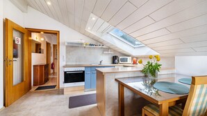 Une cuisine moderne dotée d’une verrière, de meubles en bois et d’un coin repas avec une table et des chaises.