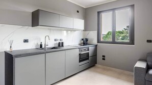 Una cucina moderna con mobili grigi, un lavello in acciaio inossidabile e un forno.