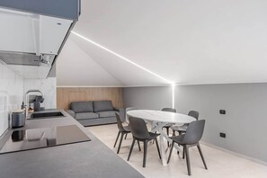 A modern kitchen with a dining area, including a round table and chairs. - Brà Apartments & Lofts (Verona)