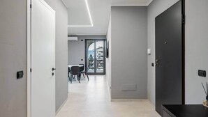 Un corridoio moderno con zona pranzo, una porta nera e vista attraverso una porta in vetro.