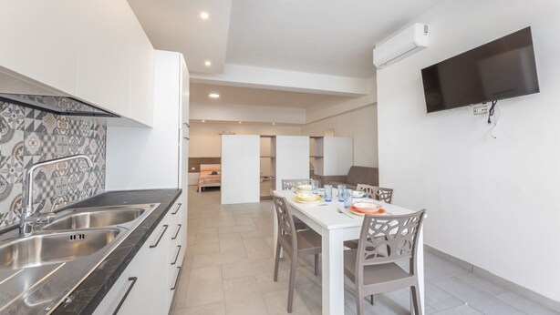 Une cuisine moderne équipée d’une cuisinière intégrée, d’un évier et d’un coin repas avec une table et des chaises.