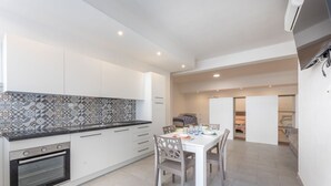 Une cuisine compacte dotée d’un four encastré, de meubles blancs et d’un crédence décorée.