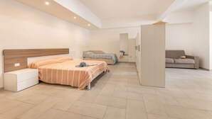 Une chambre d’hôtel avec un grand lit, un lit plus petit, un canapé, une armoire et un bureau.