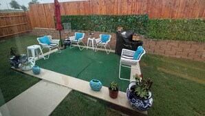 Un espace patio aménagé avec du mobilier d’extérieur, une petite table et des plantes en pot.