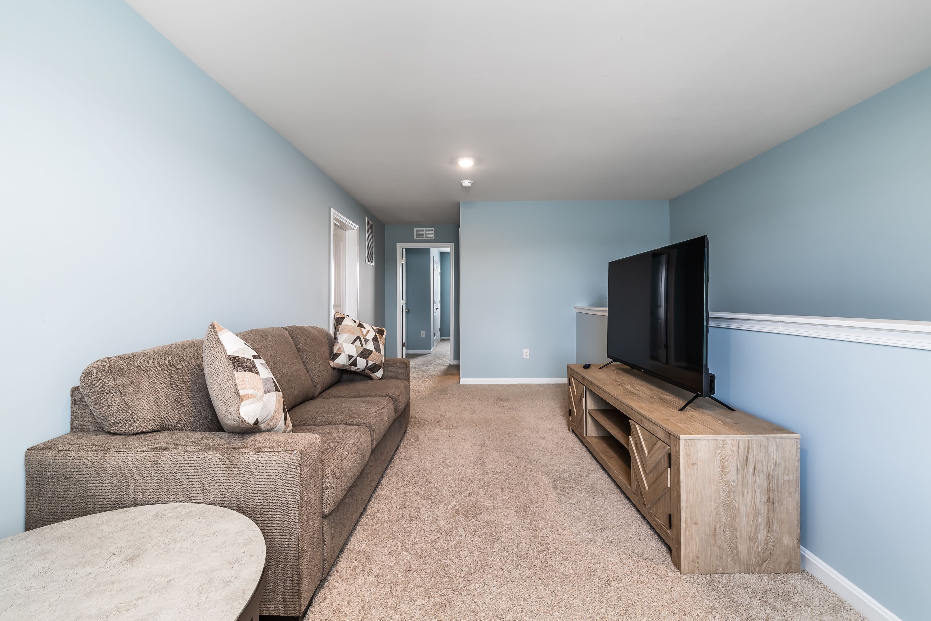 A living room with a sofa, a TV, and a wooden entertainment unit.
