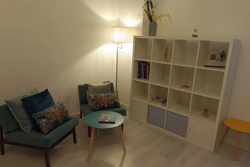 A living room with a sofa, a small round table, a bookshelf, and a floor lamp.