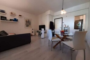 A modern living room with a sofa, dining table, chairs, and a TV. - The secret window on the Arno River (Firenze)