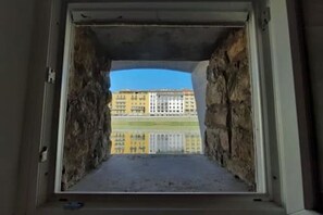 A window with a view of a building and a grassy area. - The secret window on the Arno River (Firenze)