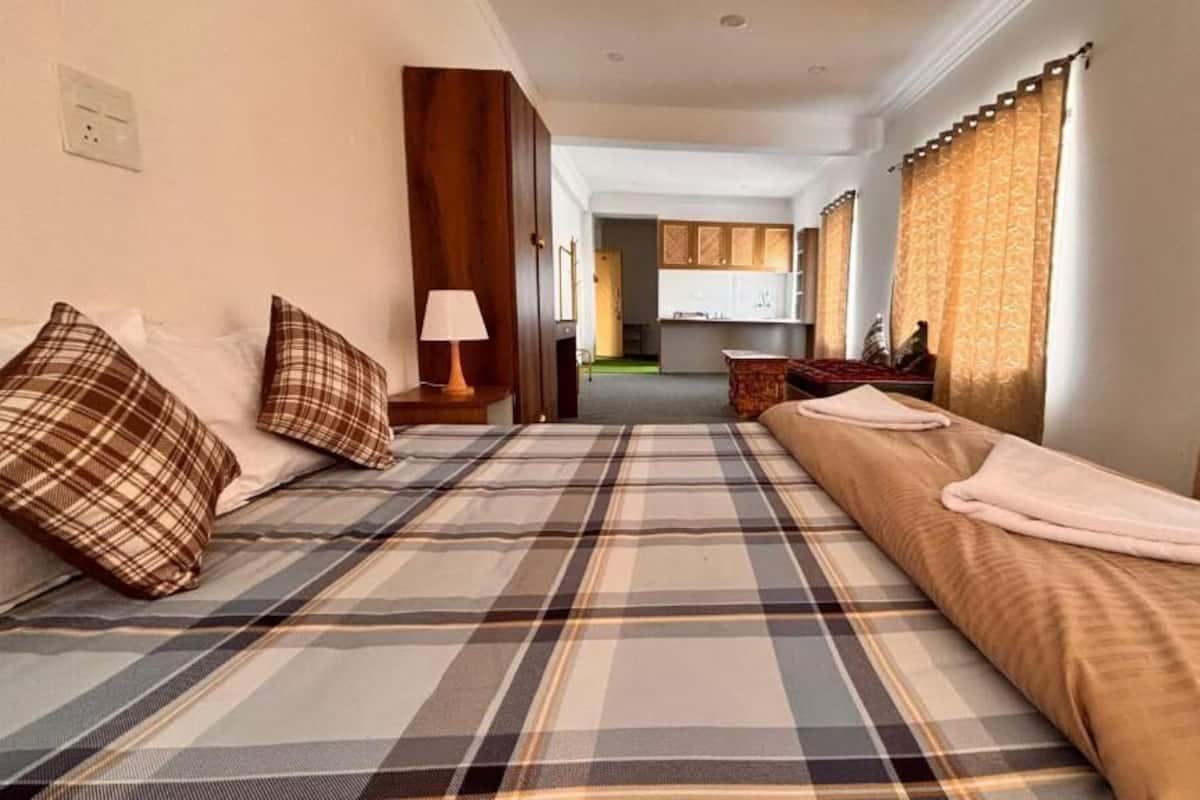 Une chambre d’hôtel comprenant un lit, une table de chevet, une lampe, un canapé, un coin cuisine et une salle de bain.