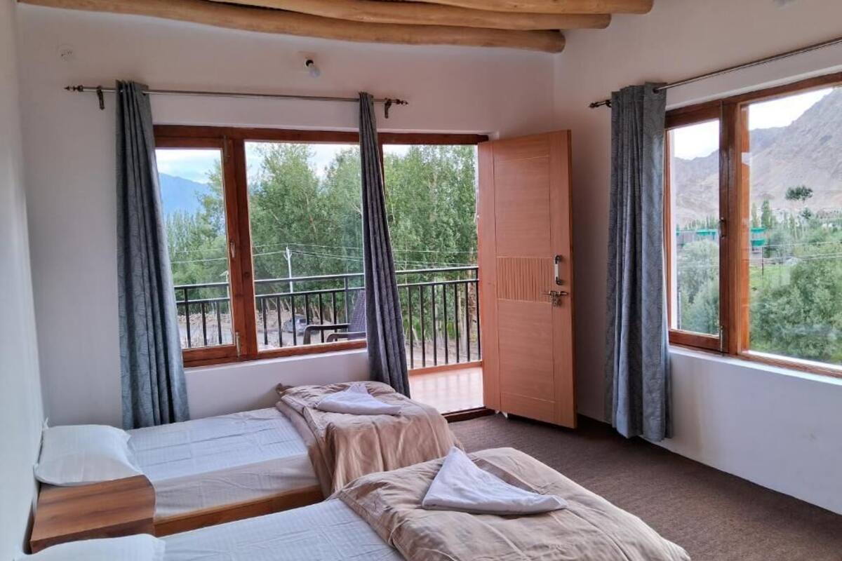 Une chambre avec deux lits, un balcon et une vue sur les montagnes.