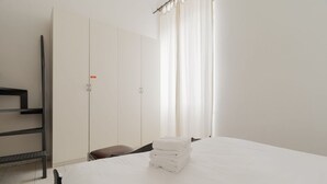 A hotel room with a bed, a wardrobe, a bench, and a window with curtains. - Comfortable 45m2 apartment, ideal for 2 people, located on the second floor of a building with lift.The accommodation is located in the Porta Romana district in a strategic position, a stone's throw from the Lodi Tibb M3 stop and the Porta Romana rai (Milan)