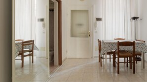 A dining area with a table and chairs, a door with a window, and a clock on the wall. - Comfortable 45m2 apartment, ideal for 2 people, located on the second floor of a building with lift.The accommodation is located in the Porta Romana district in a strategic position, a stone's throw from the Lodi Tibb M3 stop and the Porta Romana rai (Milan)