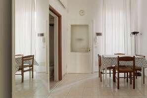 Ein Essbereich mit Tisch und Stühlen, eine Tür mit Fenster und eine Uhr an der Wand.