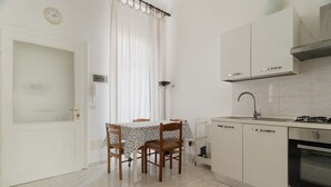 A kitchen with a dining table, chairs, a sink, cabinets, and a clock on the wall. - Comfortable 45m2 apartment, ideal for 2 people, located on the second floor of a building with lift.The accommodation is located in the Porta Romana district in a strategic position, a stone's throw from the Lodi Tibb M3 stop and the Porta Romana rai (Milan)