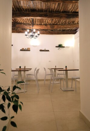 A dining area with white chairs, wooden tables, a chandelier, and a rustic ceiling. - B&B a Napoli centro: camere nel cuore della città AI 13 GRADONI DI CHIAIA (Napoli)