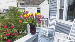 En veranda med en hvid gyngestol, et hvidt bord og en vase med tulipaner.