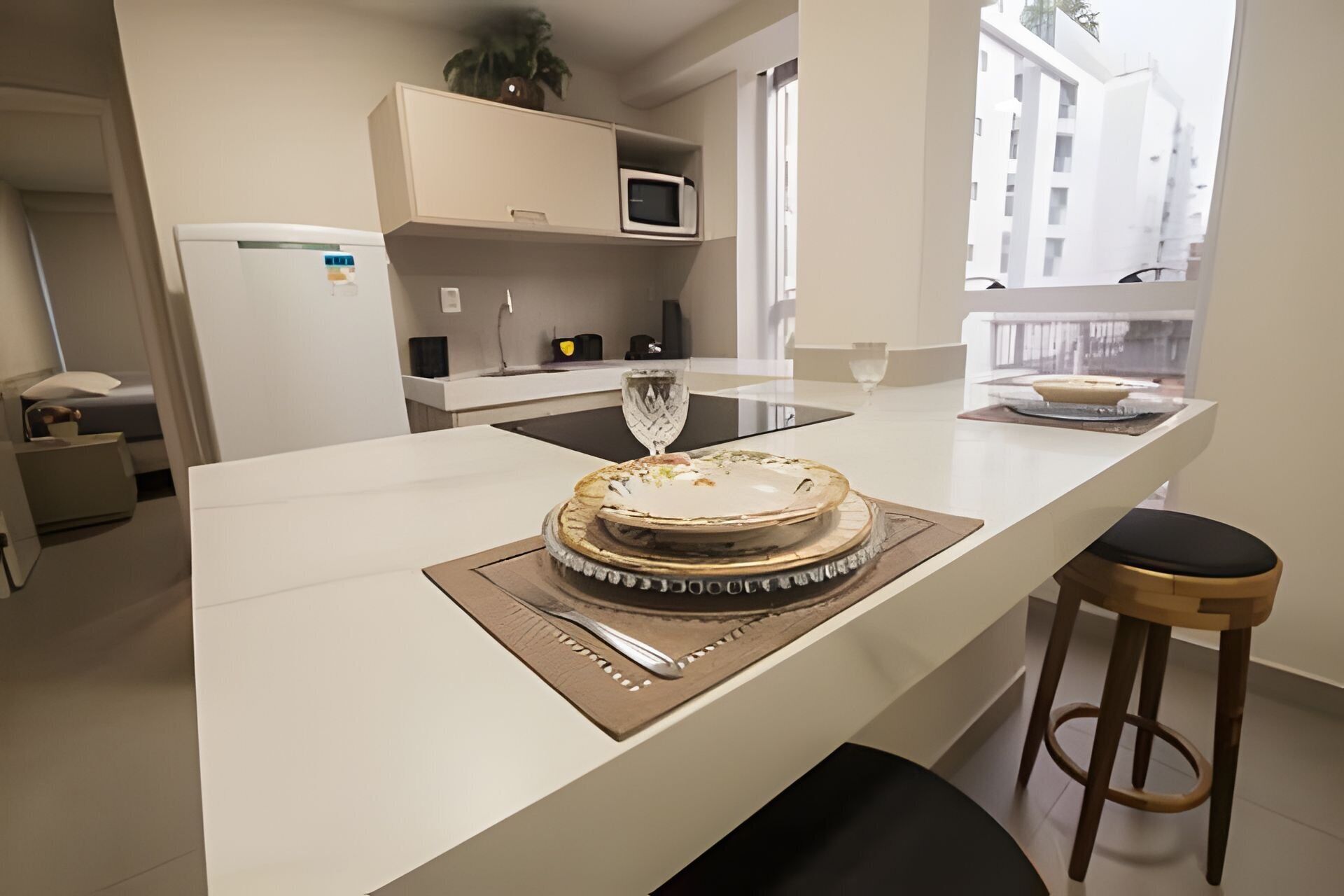 Een moderne keuken met een centraal eiland, een magnetron erboven en uitzicht op een balkon met gebouwen.