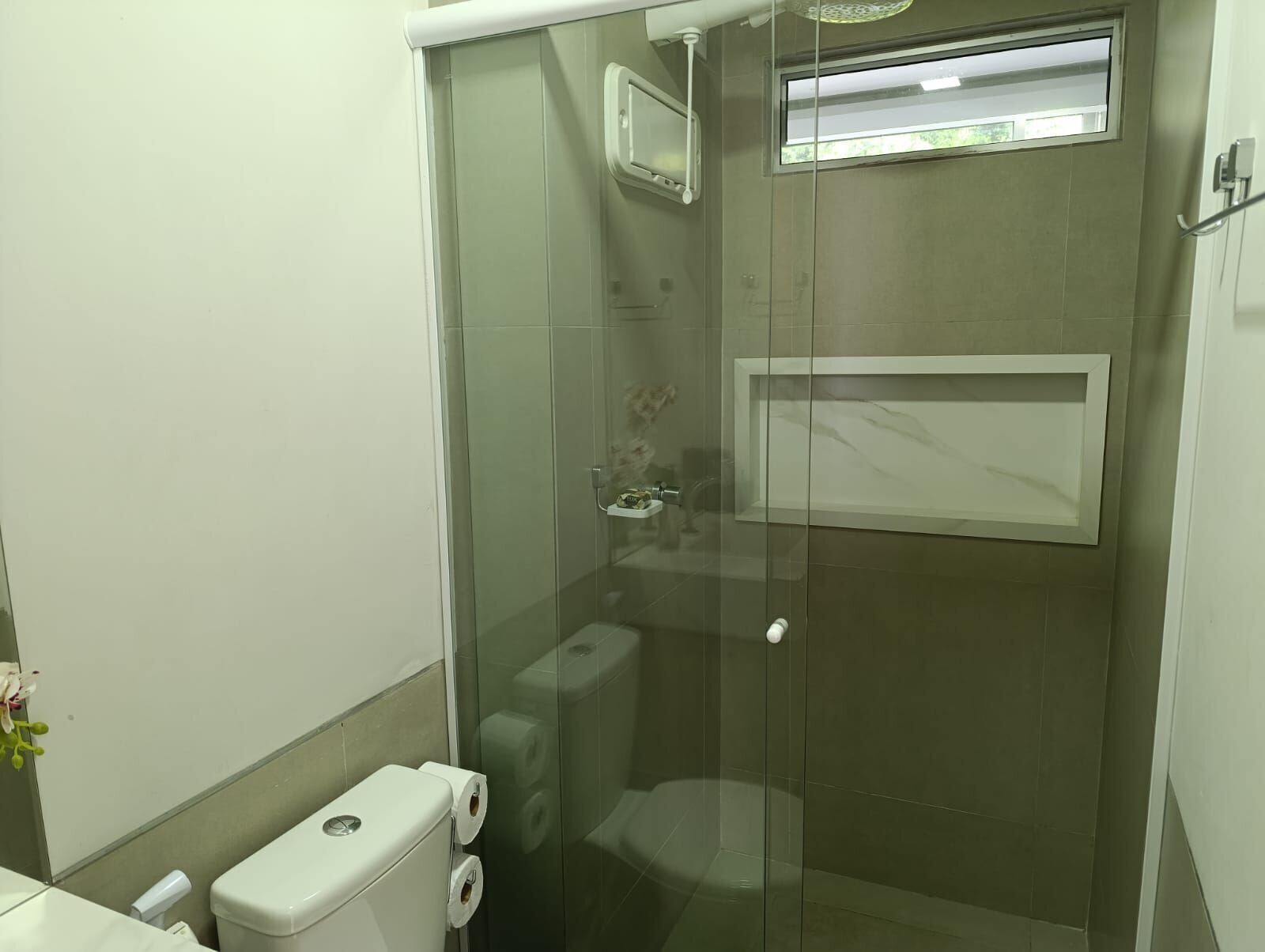 A bathroom with a glass-enclosed shower, a toilet, and a sink.