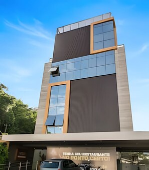 A modern building with a large glass facade, a flat roof, and a sign indicating a restaurant. - Vivendas do Mar (João Pessoa)