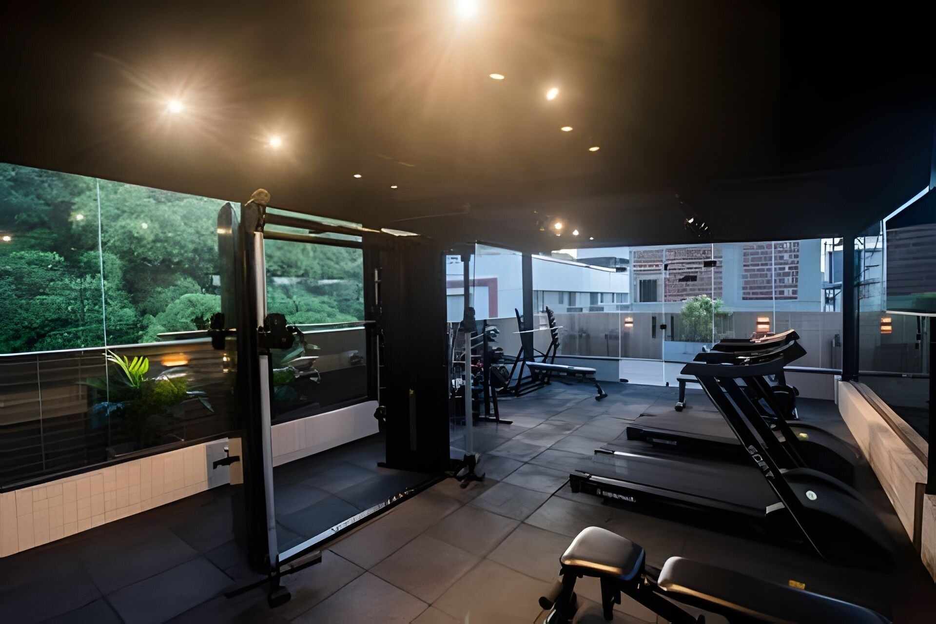 A modern gym with exercise equipment, a treadmill, and a view of greenery.