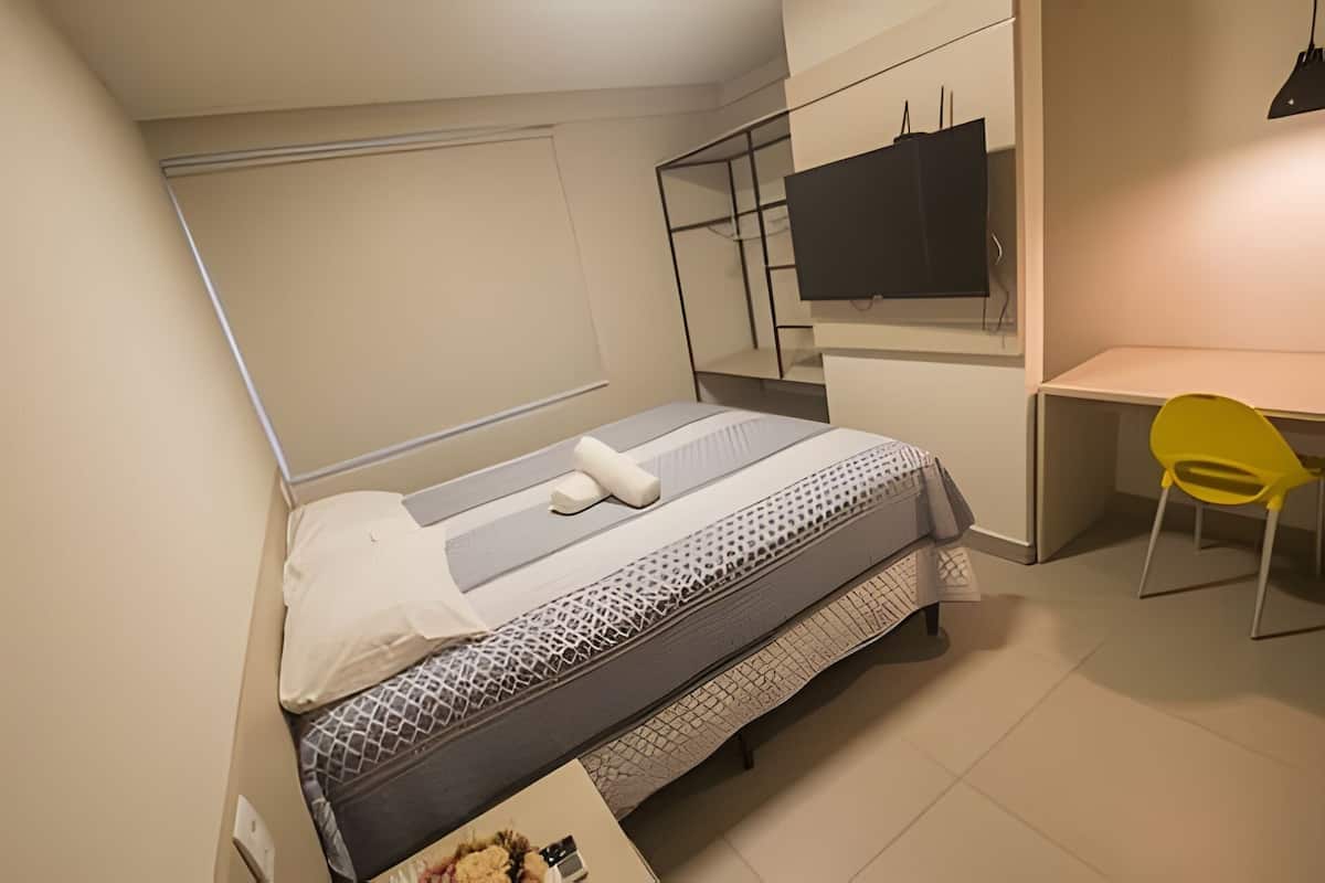 Quarto compacto com cama, escrivaninha e cadeira.
