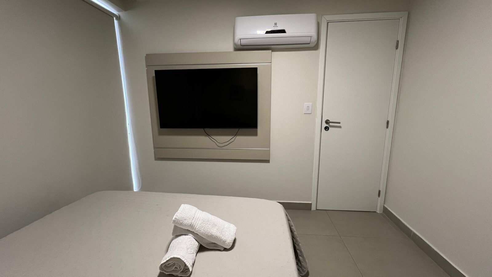 Une chambre d’hôtel équipée d’un lit, d’un téléviseur à écran plat fixé au mur, d’une porte et d’un appareil de climatisation.