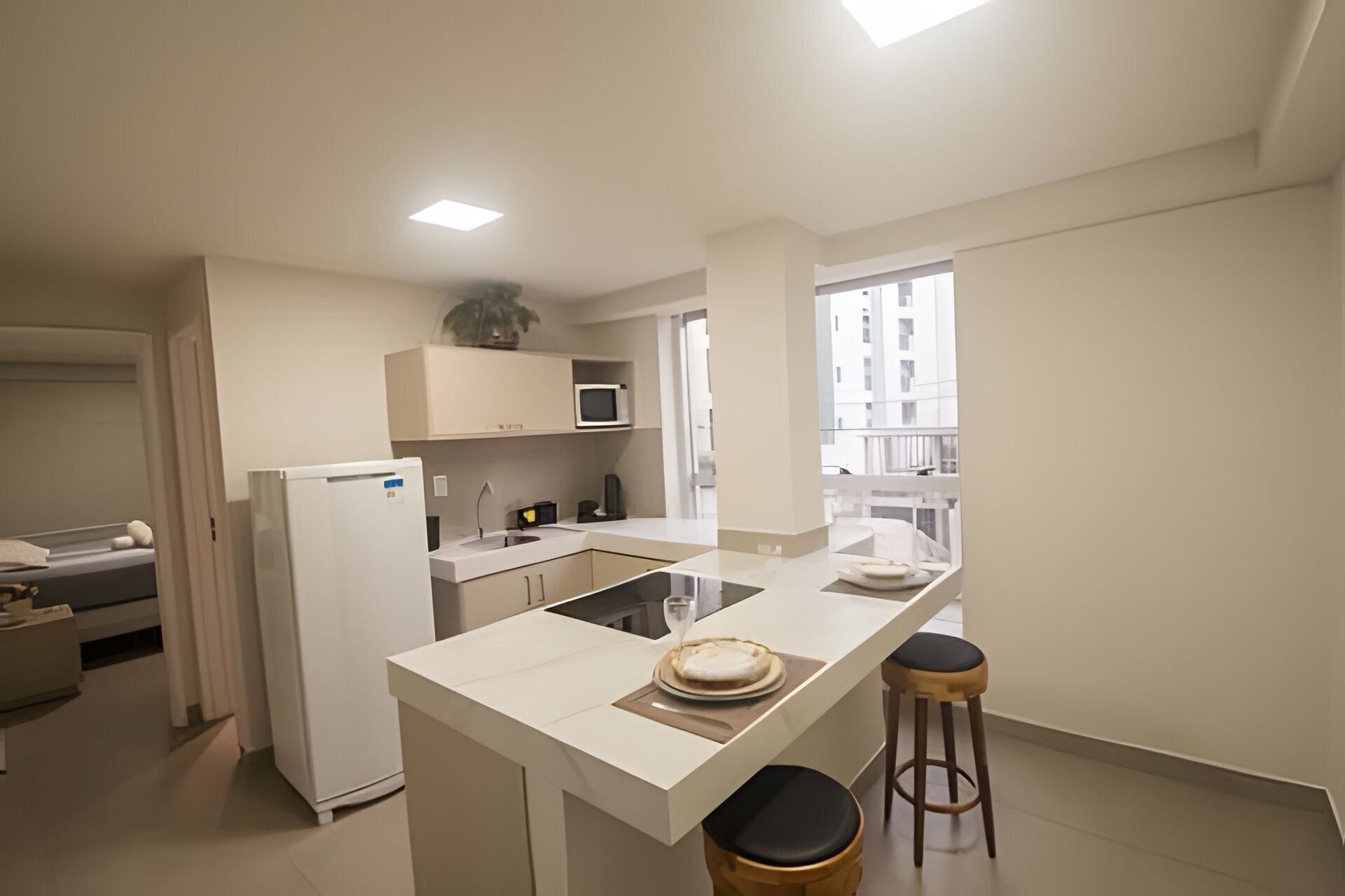 A modern kitchen with a central island, a microwave, and a refrigerator.